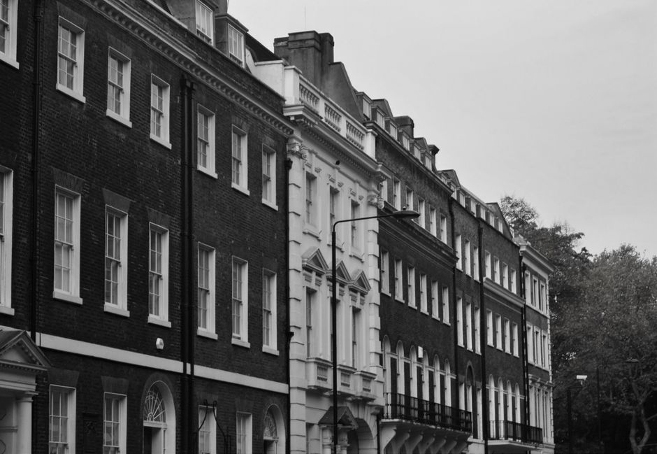 A view of residential buildings on Providence Court in Westminster SW1, featuring red brick exteriors with white-framed sash windows. The scene includes a narrow alleyway with a black metal fence, str